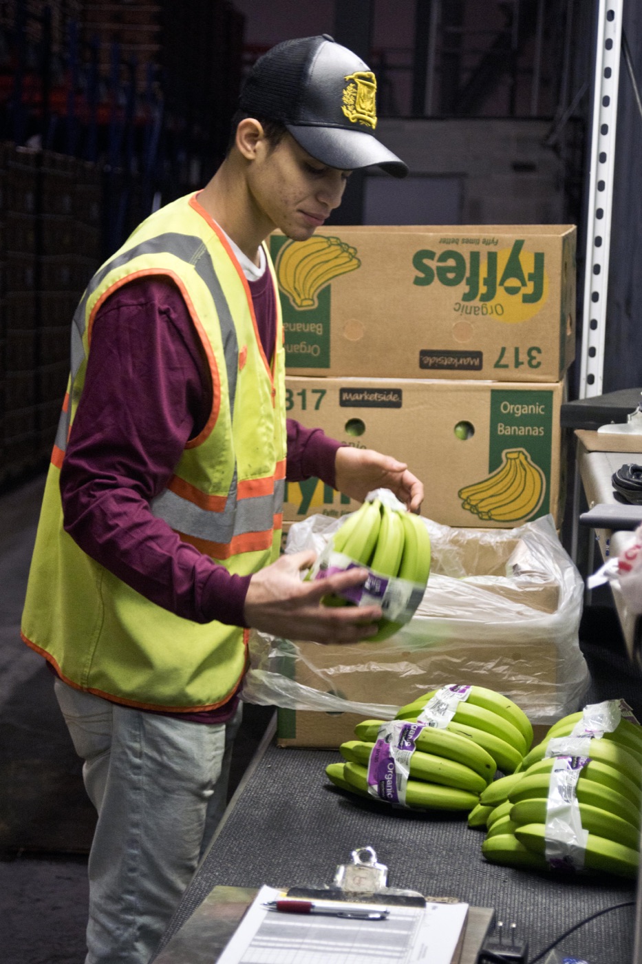 Produce worker repacking banana clusters